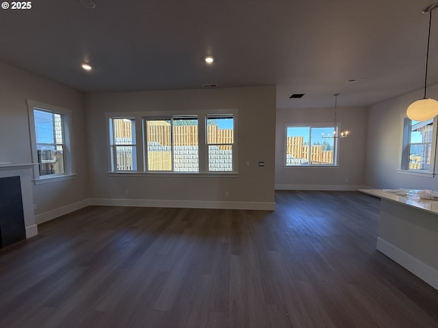 unfurnished living room featuring a notable chandelier and dark hardwood / wood-style flooring