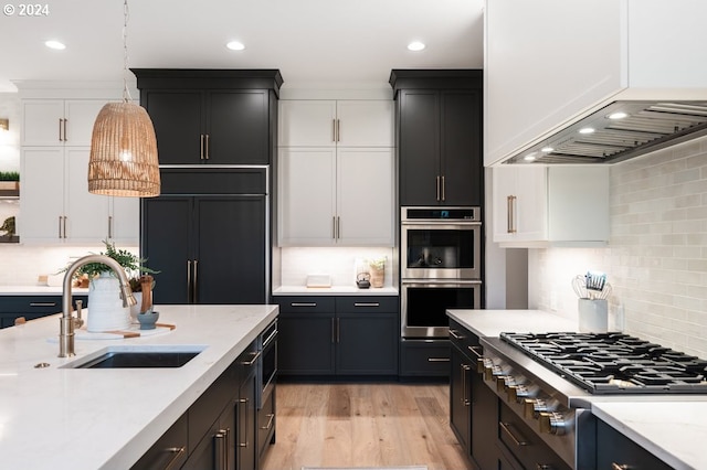kitchen with white cabinets, decorative backsplash, built in appliances, and sink