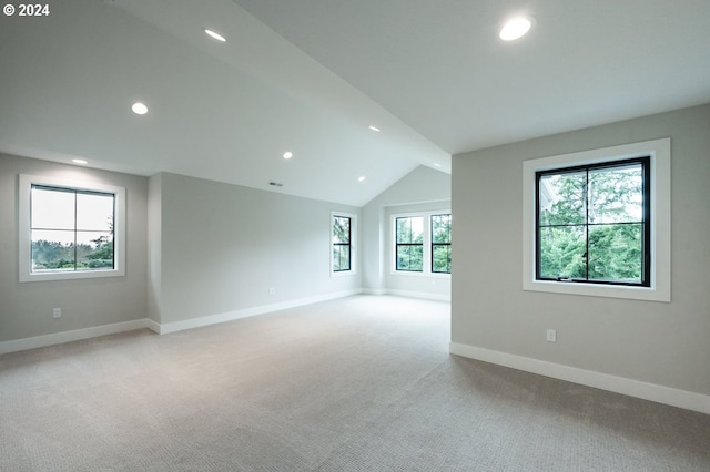 carpeted empty room with vaulted ceiling