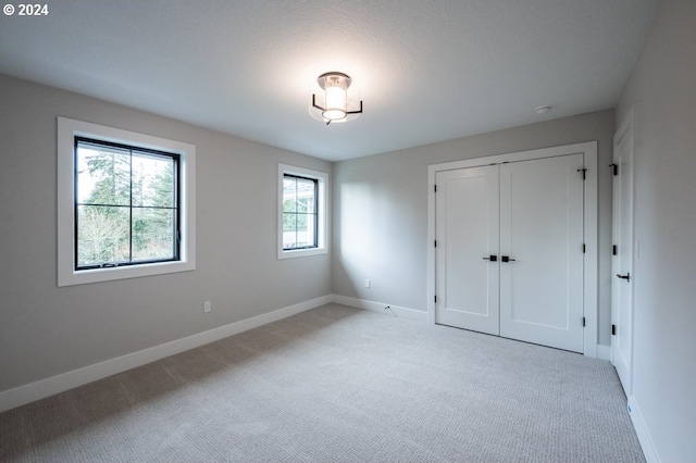 unfurnished bedroom featuring a closet and light colored carpet