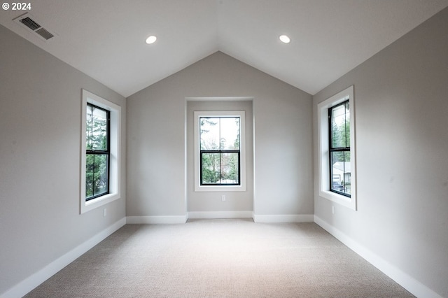 spare room featuring light colored carpet and lofted ceiling
