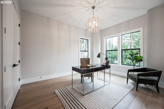 office space with plenty of natural light, wood-type flooring, and an inviting chandelier