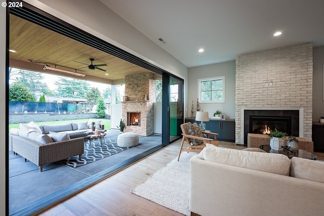 living room featuring a fireplace, light wood-type flooring, and ceiling fan