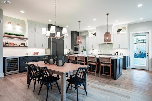 dining area featuring light hardwood / wood-style floors, beverage cooler, a notable chandelier, and sink