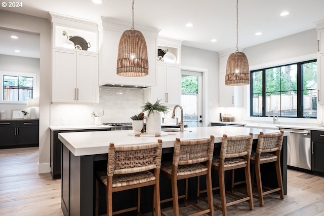 kitchen featuring white cabinetry, dishwasher, a center island with sink, and sink