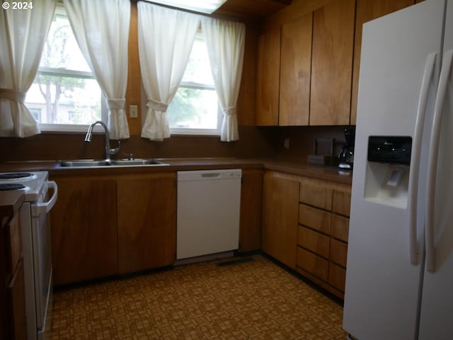 kitchen featuring white appliances, a wealth of natural light, and sink