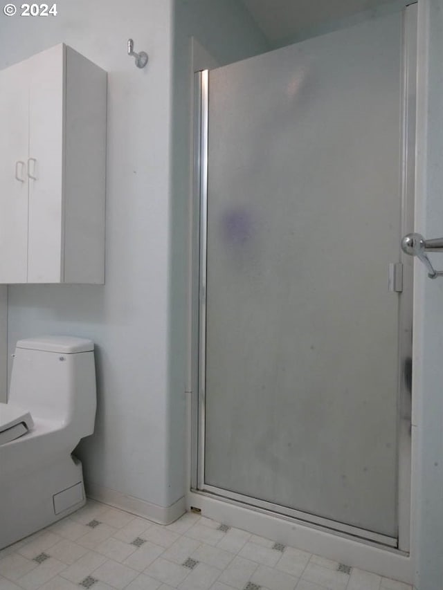 bathroom with a shower with shower door and toilet