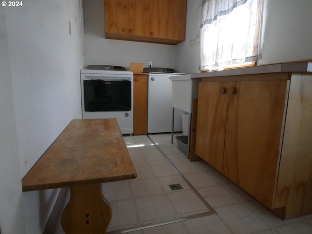 clothes washing area featuring separate washer and dryer and cabinets