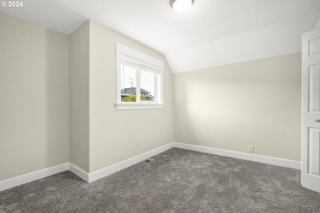 bonus room featuring vaulted ceiling, dark carpet, and a textured ceiling