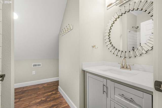 bathroom with hardwood / wood-style floors, vanity, and lofted ceiling