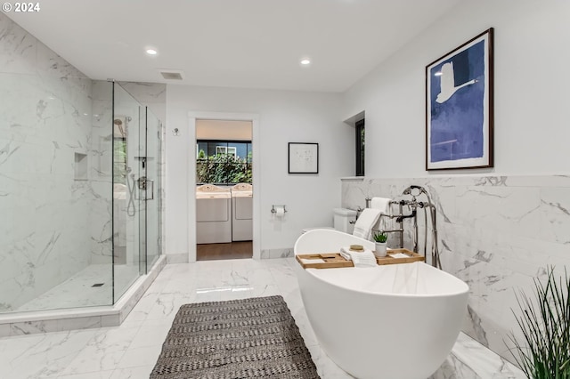 full bathroom with shower with separate bathtub, toilet, tile walls, vanity, and washer and clothes dryer