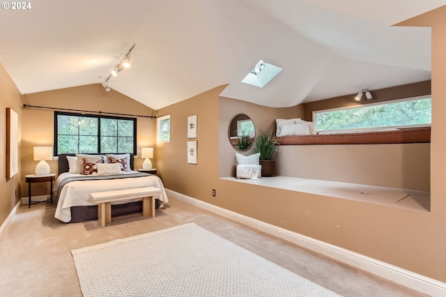 bedroom with light carpet, vaulted ceiling with skylight, and track lighting