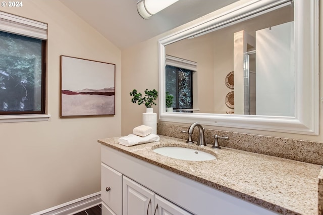 bathroom with vanity, lofted ceiling, and a shower with door