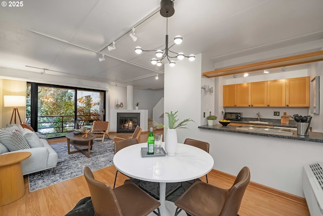 dining area featuring light wood-type flooring, rail lighting, and a chandelier