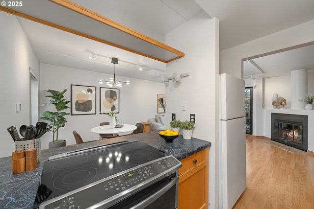 kitchen with light hardwood / wood-style floors, range with electric cooktop, and fridge