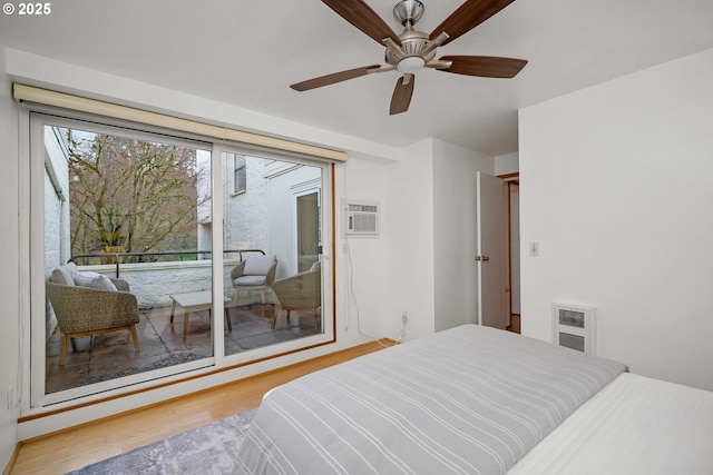 bedroom with hardwood / wood-style flooring, access to outside, an AC wall unit, ceiling fan, and heating unit