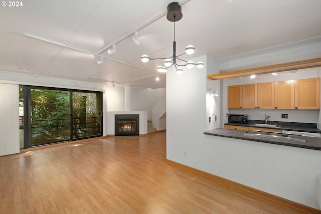 interior space featuring rail lighting, an inviting chandelier, sink, and light hardwood / wood-style flooring