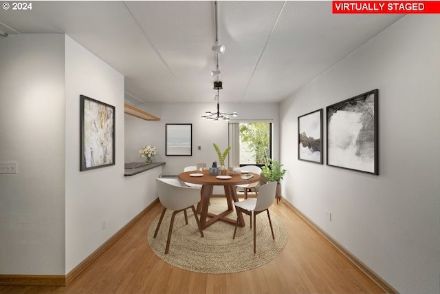 dining space with an inviting chandelier, light wood-type flooring, and track lighting