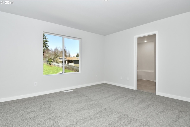 unfurnished room featuring carpet and baseboards