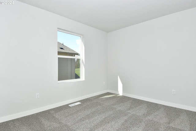 unfurnished room featuring carpet, visible vents, and baseboards