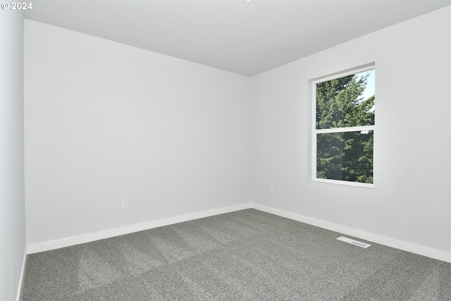 unfurnished room with dark carpet, visible vents, and baseboards