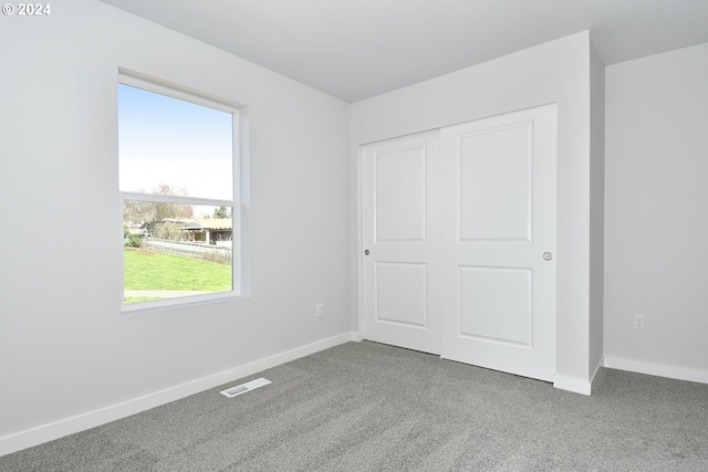 unfurnished bedroom with multiple windows, a closet, and carpet