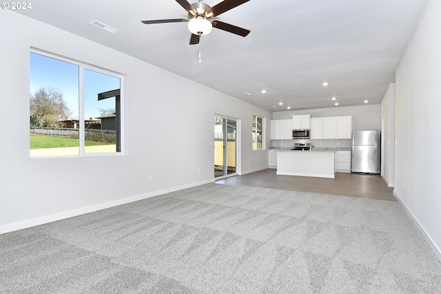 unfurnished living room with ceiling fan, recessed lighting, carpet flooring, visible vents, and baseboards