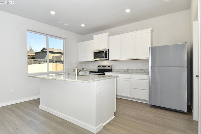 kitchen featuring light wood finished floors, visible vents, stainless steel appliances, white cabinetry, and a sink