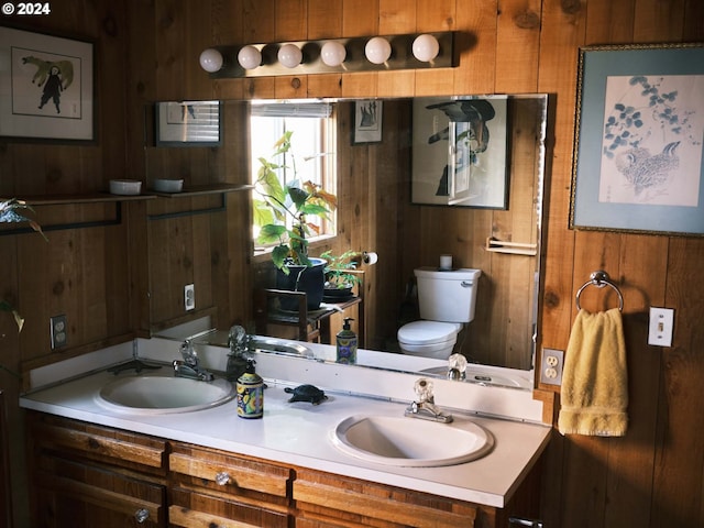 bathroom featuring toilet, wood walls, and vanity