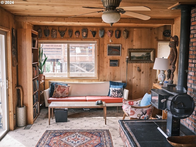 living room featuring wood walls, a wood stove, wooden ceiling, brick wall, and ceiling fan