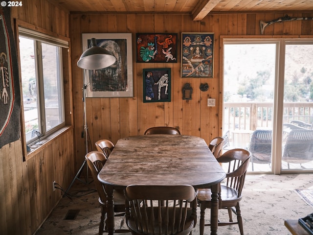 dining area featuring wood ceiling, carpet floors, wooden walls, and plenty of natural light