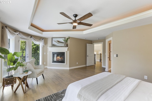 bedroom with a raised ceiling, ceiling fan, wood-type flooring, and ornamental molding