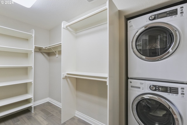 laundry room featuring wood-type flooring and stacked washer and dryer