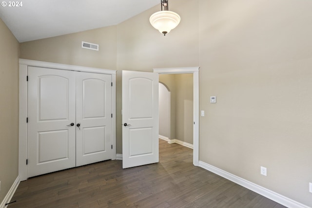 unfurnished bedroom with dark hardwood / wood-style flooring, a closet, and vaulted ceiling