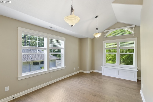 unfurnished room featuring lofted ceiling, light hardwood / wood-style flooring, and a healthy amount of sunlight