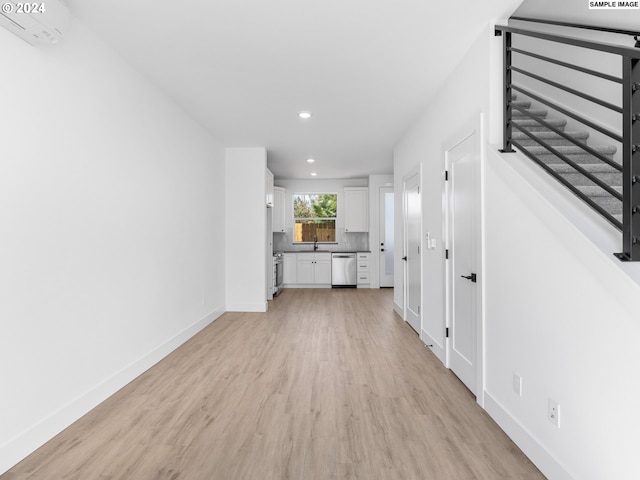 unfurnished living room featuring light wood finished floors, recessed lighting, a sink, and baseboards