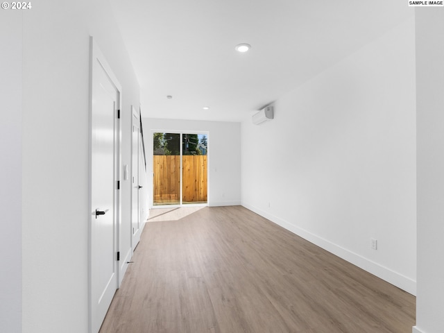 interior space featuring recessed lighting, a wall unit AC, wood finished floors, and baseboards
