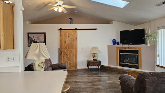 4072 Forsythia St, Springfield, OR 97478 - living room featuring vaulted ceiling, dark wood finished floors, a barn door, a ceiling fan, and a glass covered fireplace
