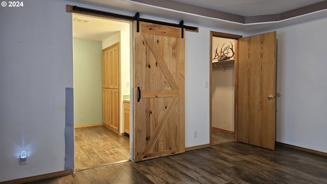 4072 Forsythia St, Springfield, OR 97478 - unfurnished bedroom featuring a barn door, dark wood-type flooring, and baseboards