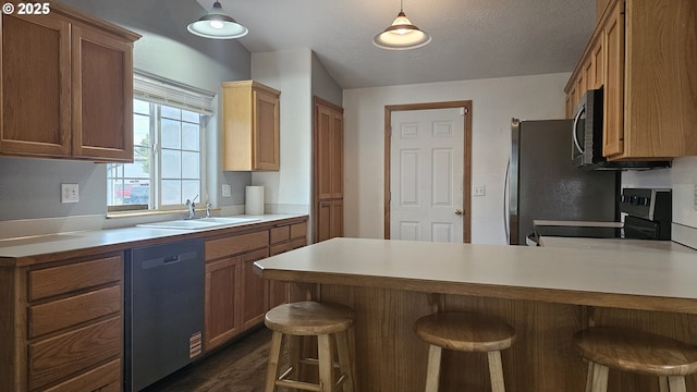 4072 Forsythia St, Springfield, OR 97478 - kitchen featuring appliances with stainless steel finishes, a peninsula, light countertops, a kitchen bar, and dark wood finished floors