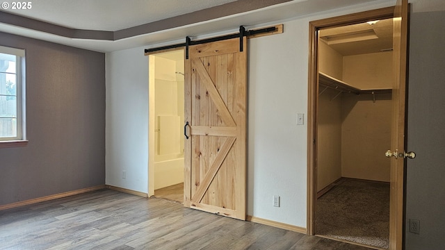 4072 Forsythia St, Springfield, OR 97478 - unfurnished bedroom with a walk in closet, a barn door, wood finished floors, a closet, and connected bathroom