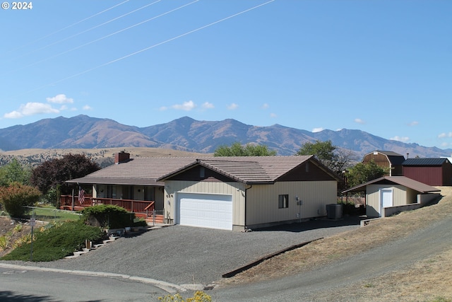 view of front facade with a mountain view, a storage unit, a garage, and cooling unit