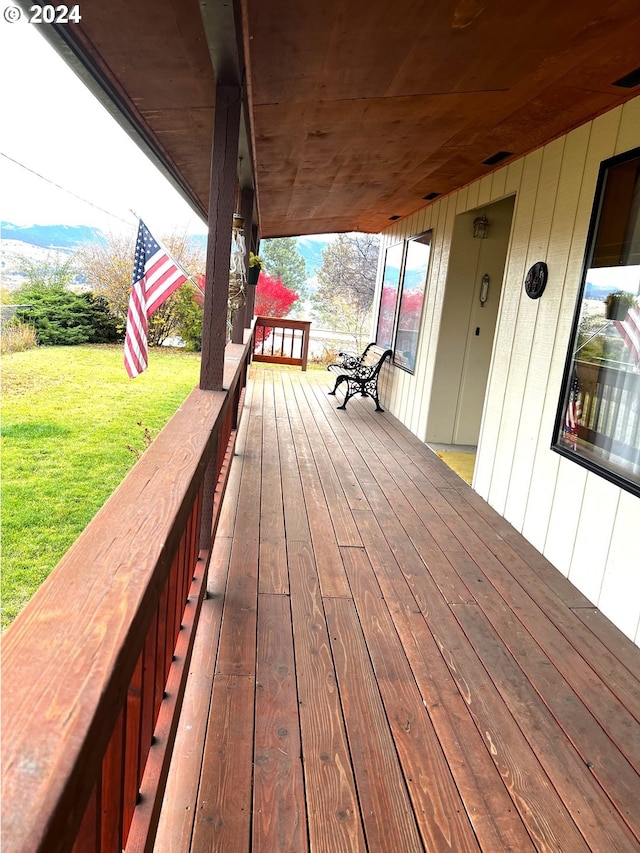 wooden terrace with a lawn and a porch