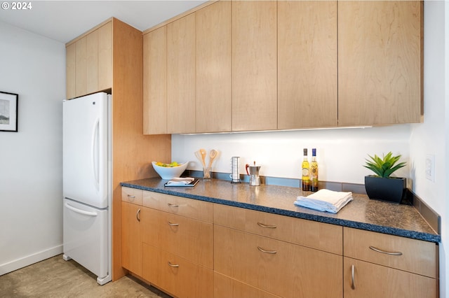 kitchen featuring light brown cabinetry and white refrigerator