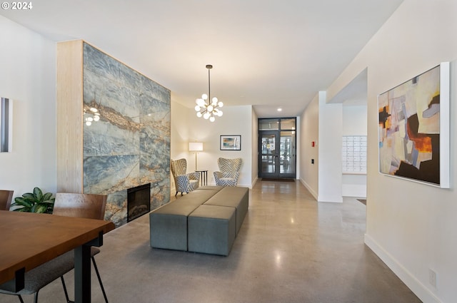 living room featuring concrete floors, a large fireplace, and a notable chandelier