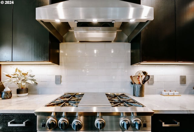 1930 S River Dr Unit W107, Portland, OR 97201 - kitchen with dark cabinetry, light stone countertops, wall chimney range hood, range, and backsplash