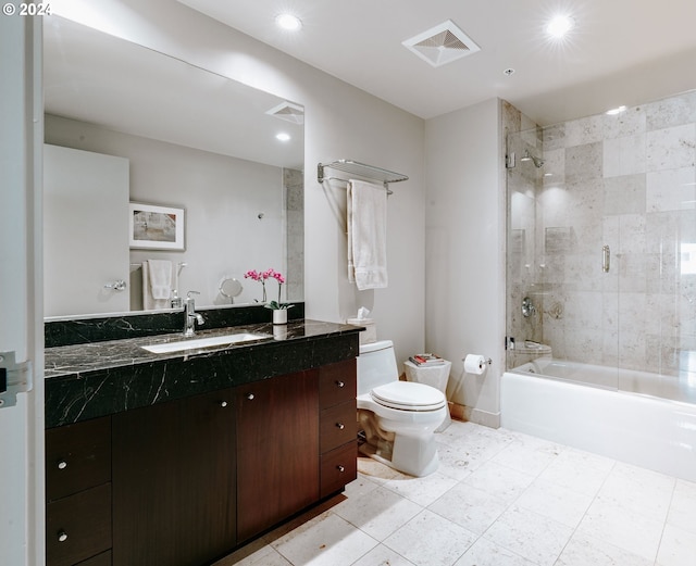 full bathroom featuring vanity with extensive cabinet space, tiled shower / bath, toilet, and tile flooring