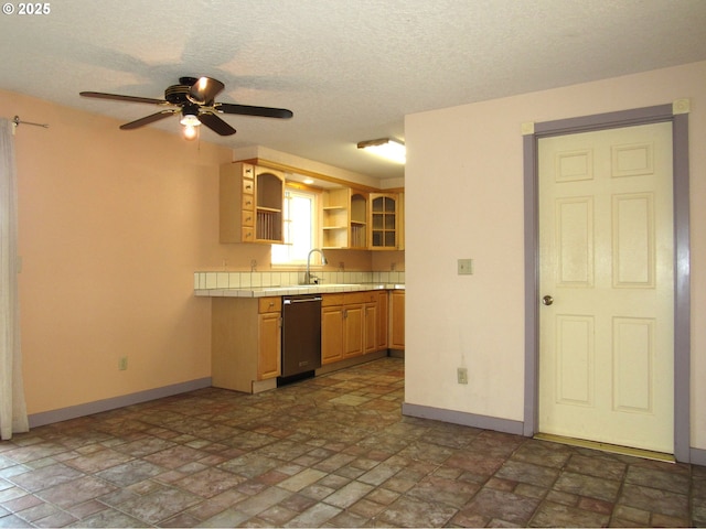 kitchen with sink, ceiling fan, black dishwasher, a textured ceiling, and tile countertops