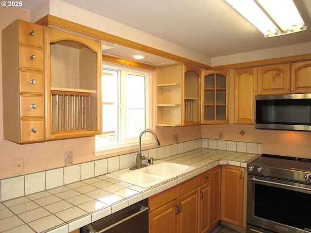 kitchen featuring stainless steel appliances, sink, and tile counters