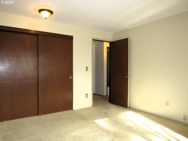 unfurnished bedroom with light carpet, a closet, and a textured ceiling